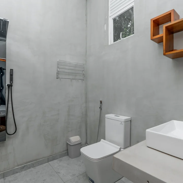 Modern hotel bathroom with rainfall shower panel and minimalist concrete walls