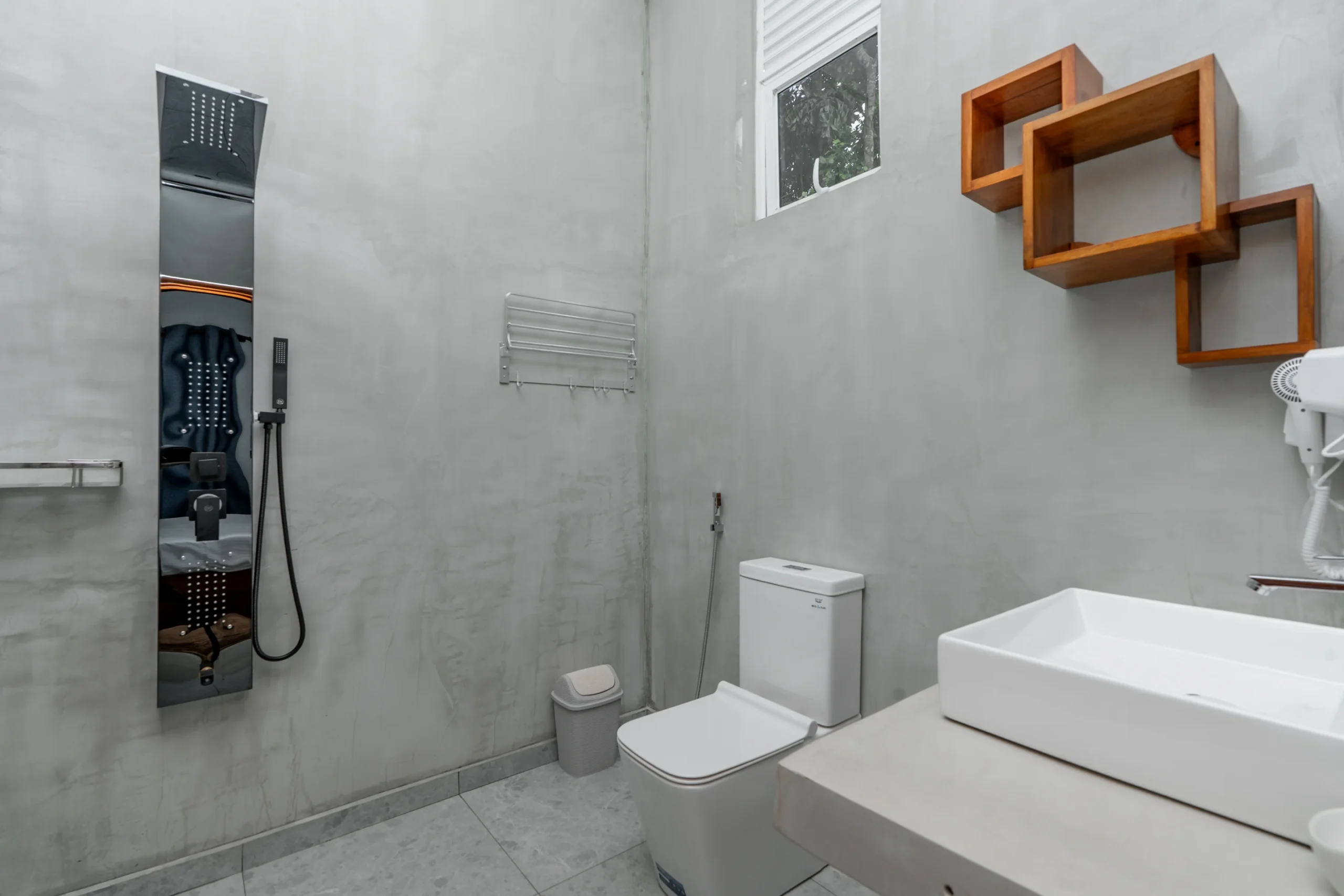 Modern hotel bathroom with rainfall shower panel and minimalist concrete walls