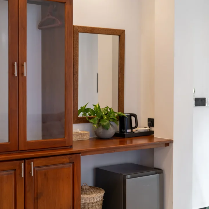 Hotel minibar area with wooden cabinetry and compact refrigerator
