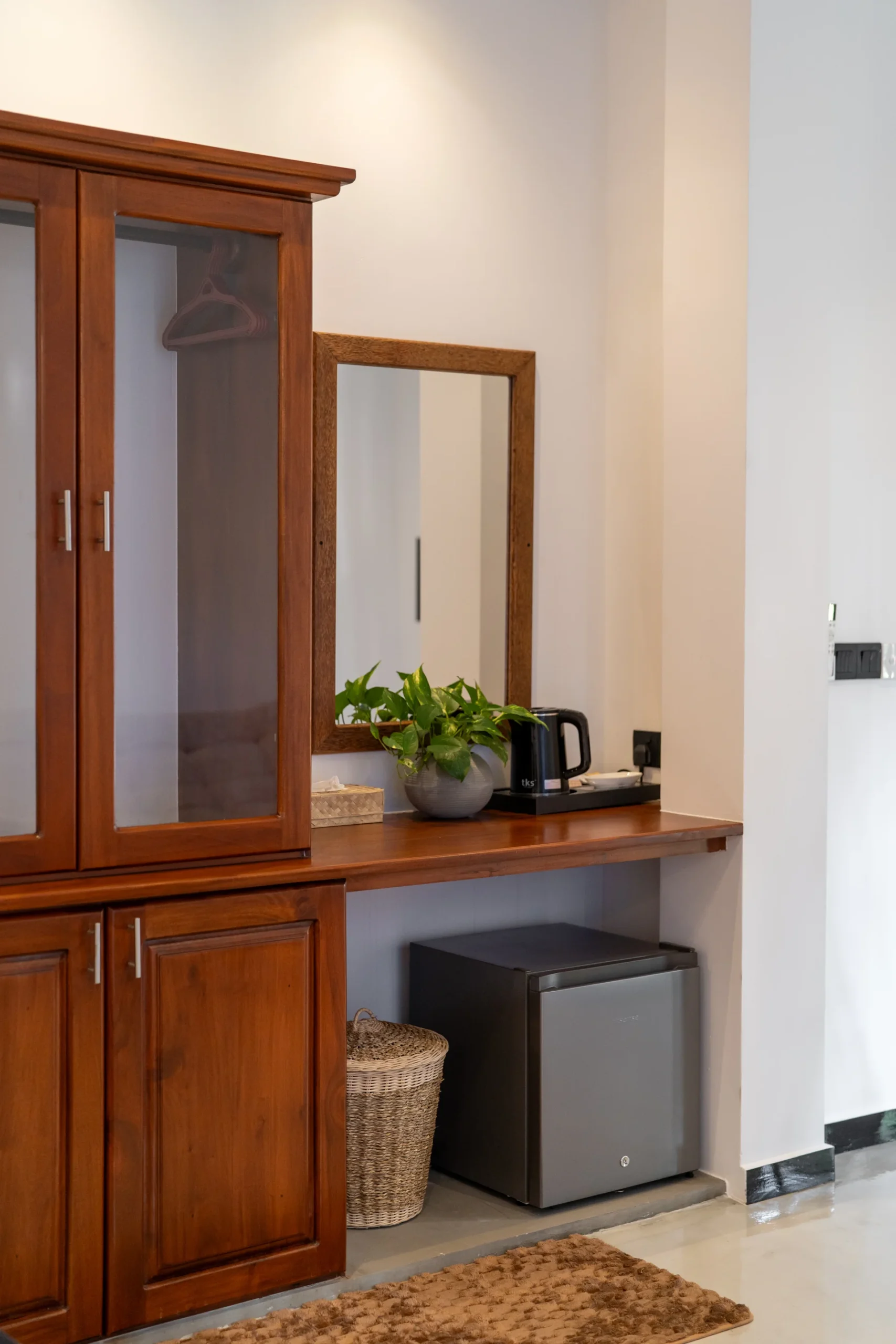 Hotel minibar area with wooden cabinetry and compact refrigerator