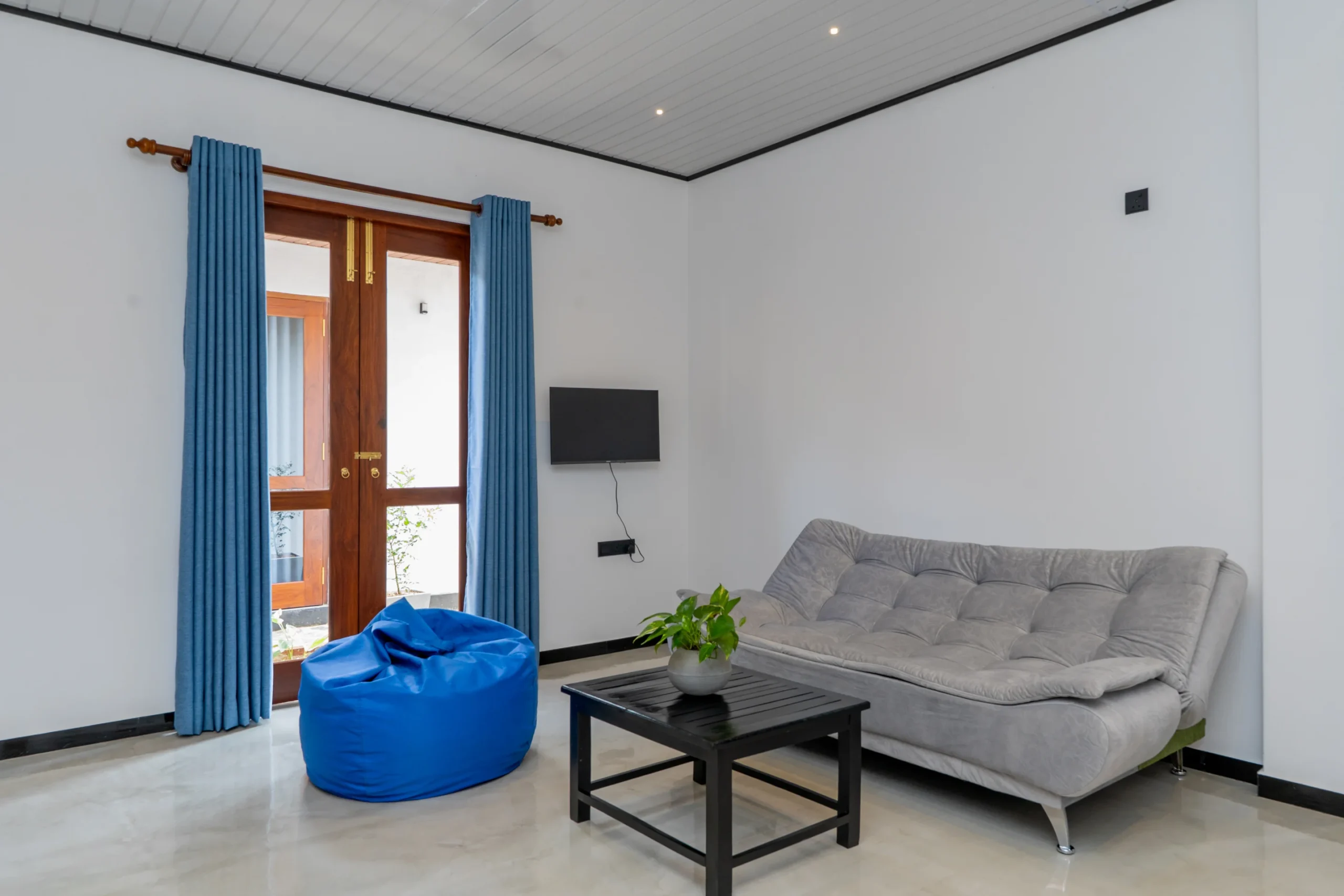 Comfortable hotel lounge area with grey sofa, bean bag, and balcony doors