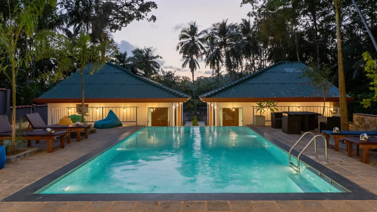 Symmetrical view of two poolside villa rooms with illuminated interiors at Arice Eco Villa