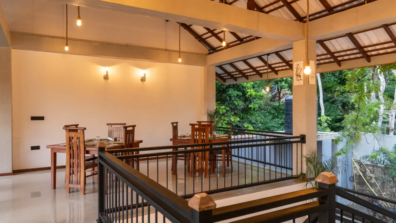 Open dining area with wooden furniture and forest backdrop at Arice Eco Villa